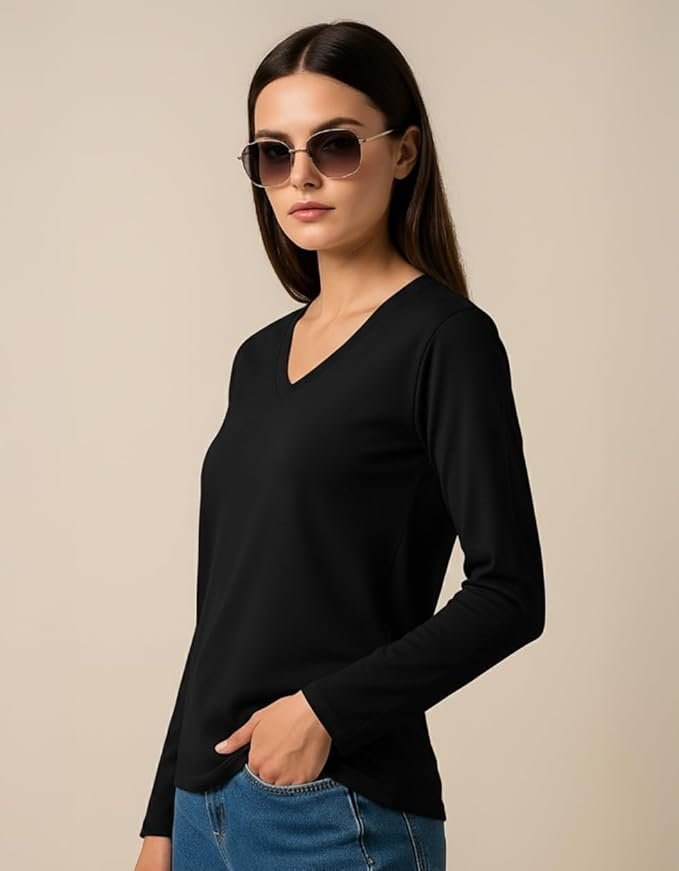 Woman wearing a black V-neck long-sleeve top with blue jeans and sunglasses, posing against a beige background.