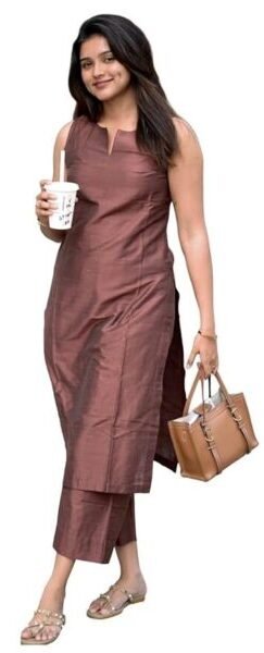 Woman wearing a sleeveless brown kurta set with straight pants, carrying a handbag and coffee cup against a plain background.