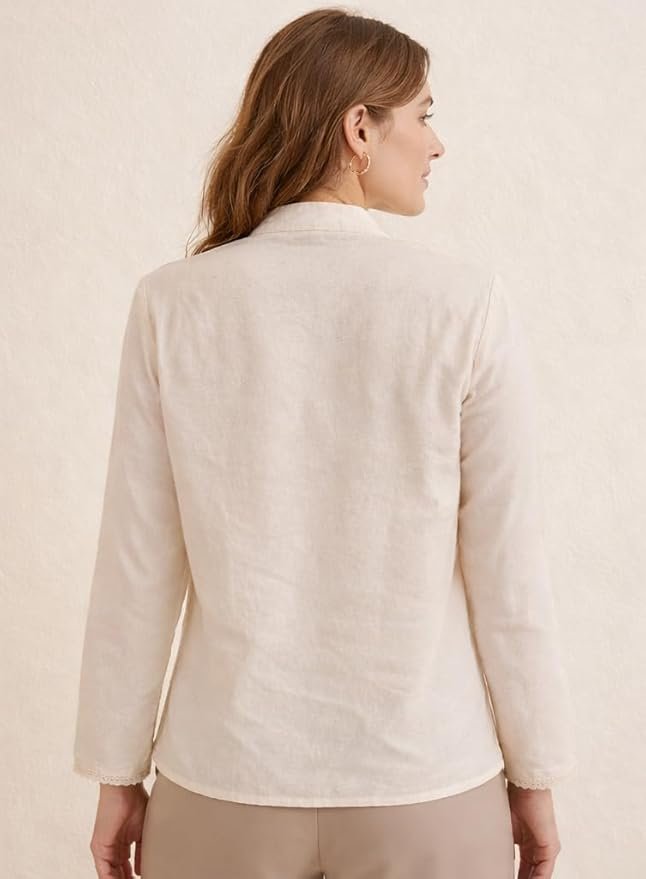 Woman wearing a cream embroidered button-down top with floral detailing and long sleeves, styled with beige pants.
