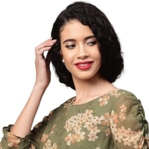 Woman wearing a sage green floral blouse with a cream midi skirt, beige heels, and a matching handbag against a grey background