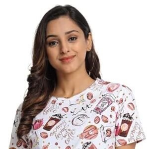 Woman wearing a white graphic print t-shirt with coffee-themed illustrations and black jeans against a plain background.