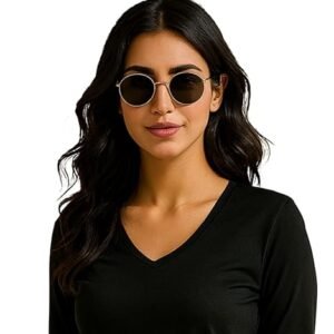 Woman wearing a black V-neck long-sleeve top with blue jeans and sunglasses, posing against a beige background.