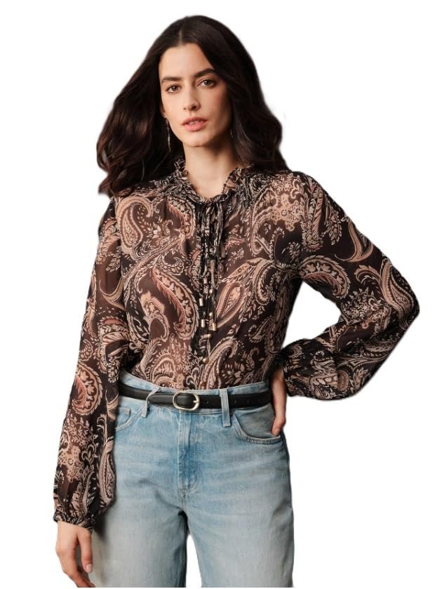 Woman wearing a brown paisley print blouse with long sleeves, paired with light blue jeans against a plain background.