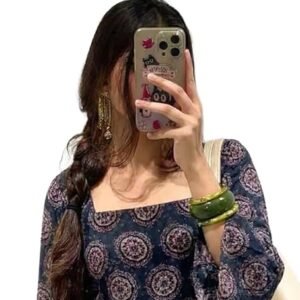 Woman wearing a navy blue printed ethnic top with bell sleeves and grey jeans carrying a cream shoulder bag