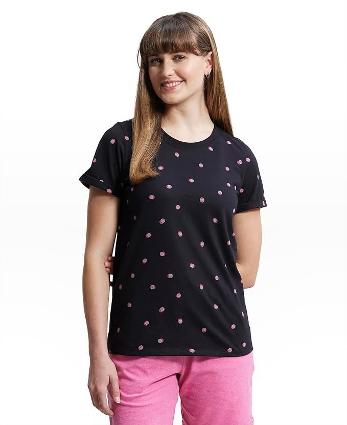 Woman wearing a black polka dot t-shirt paired with pink pants, posing against a plain background.