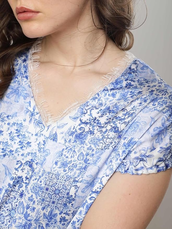 Woman wearing a blue floral print V-neck top with short puff sleeves, posing against a white background.