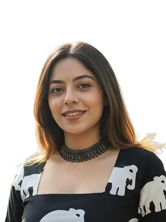 Woman wearing a black long-sleeve top with white elephant prints and a square neckline, posing against a plain background.
